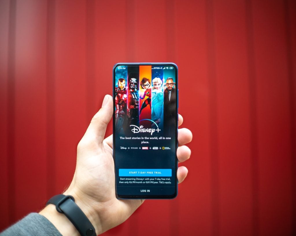 Una mano sujetando un teléfono inteligente con Disney Plus en su pantalla