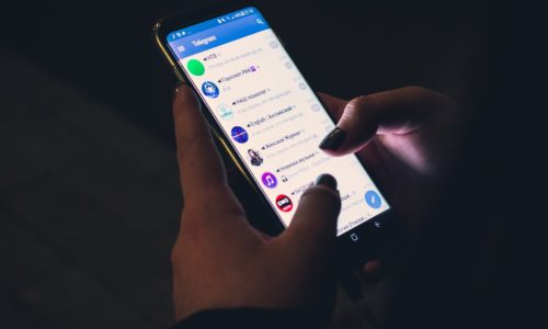 Unas manos sostienen un celular con la interfaz de Telegram en su pantalla